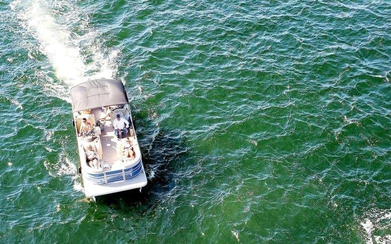 Overhead view of speeding houseboat in the ocean during summertime activities at sea.