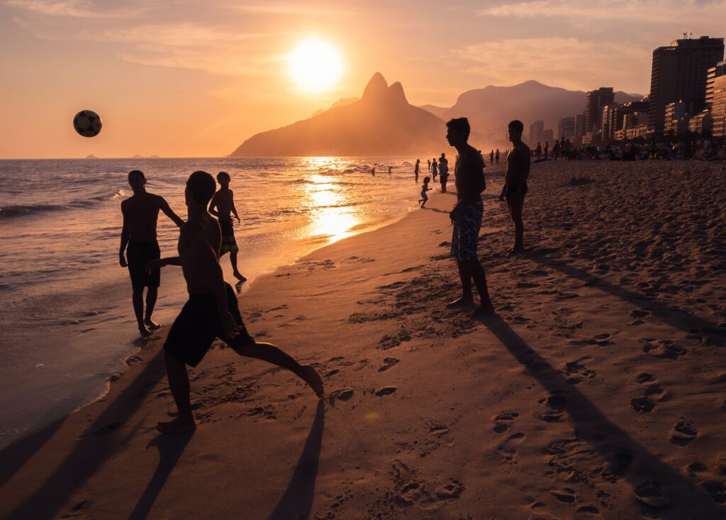 Rio de Janeiro, Brazil - February 13 2014: Young men throwing ball on beach during sunset