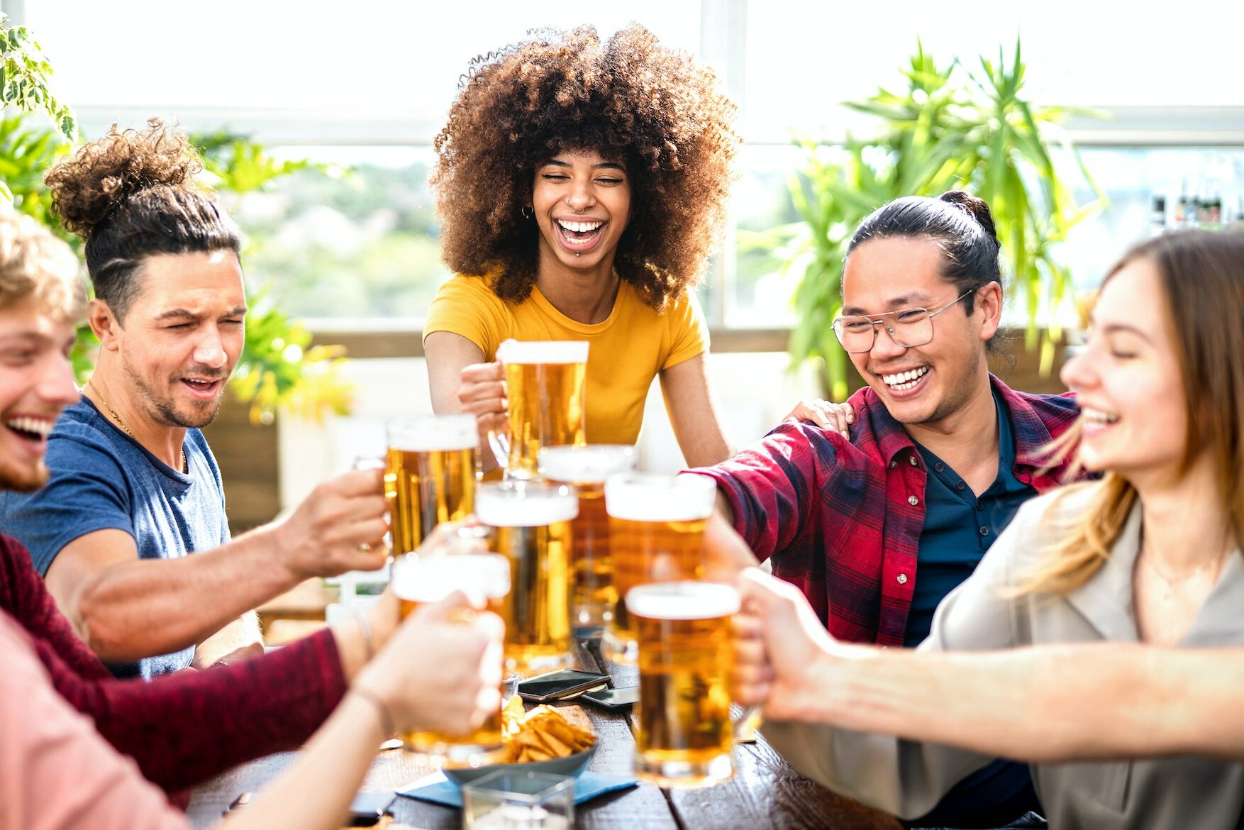 Young trendy people drinking and toasting beer at brewery bar restaurant
