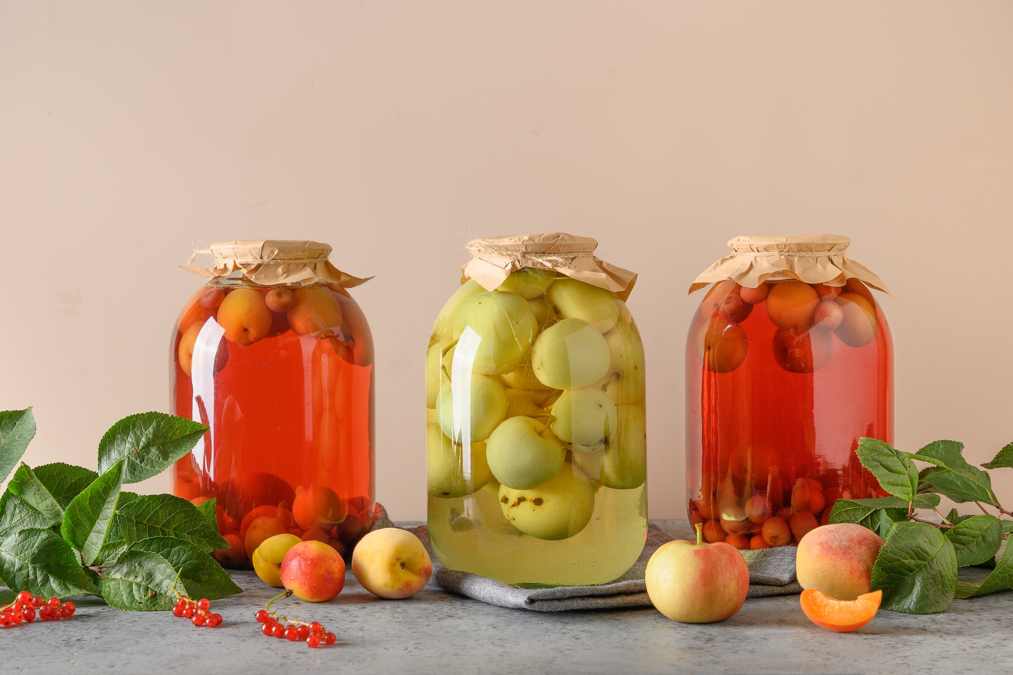 Three homemade canned fruits apple and cherry compote in large glass jars.