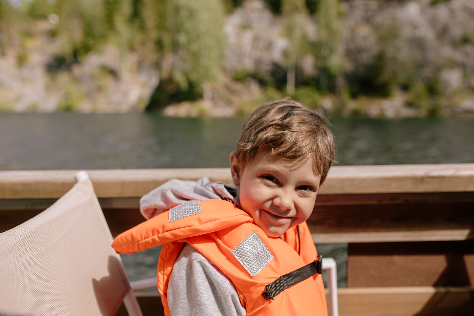 Cute little boy wearing safety vest going by boat in canyon