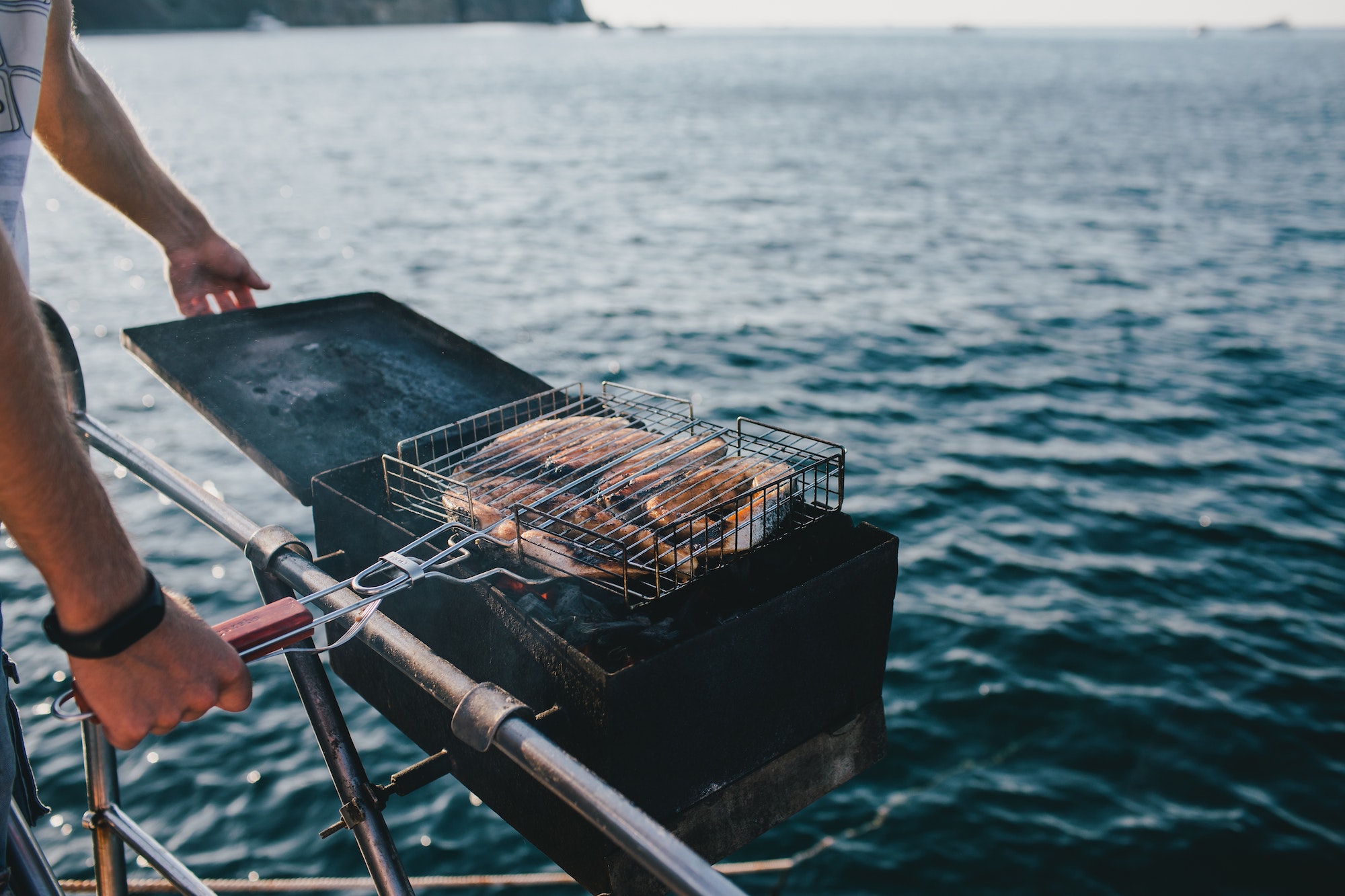 Man making barbecue fish on boat with beautiful sea view