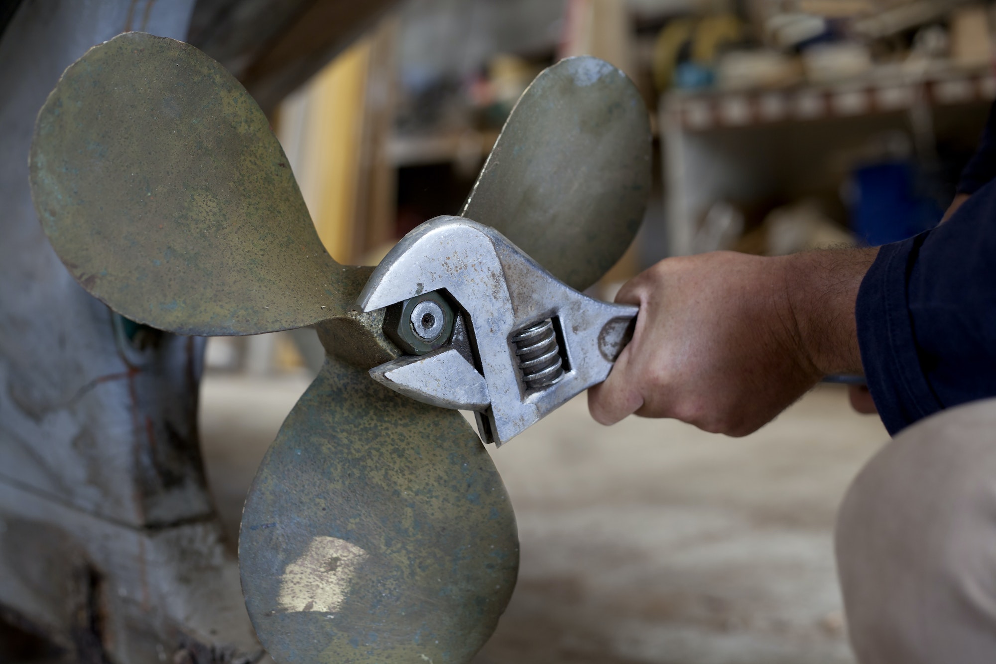 Man tightening boat propeller in workshop