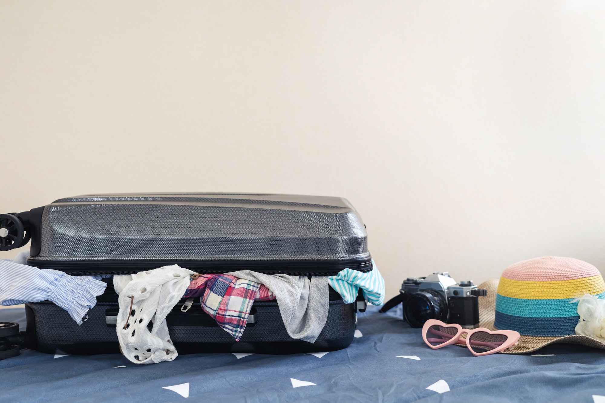 Young woman traveler packing her clothes and stuff in suitcase