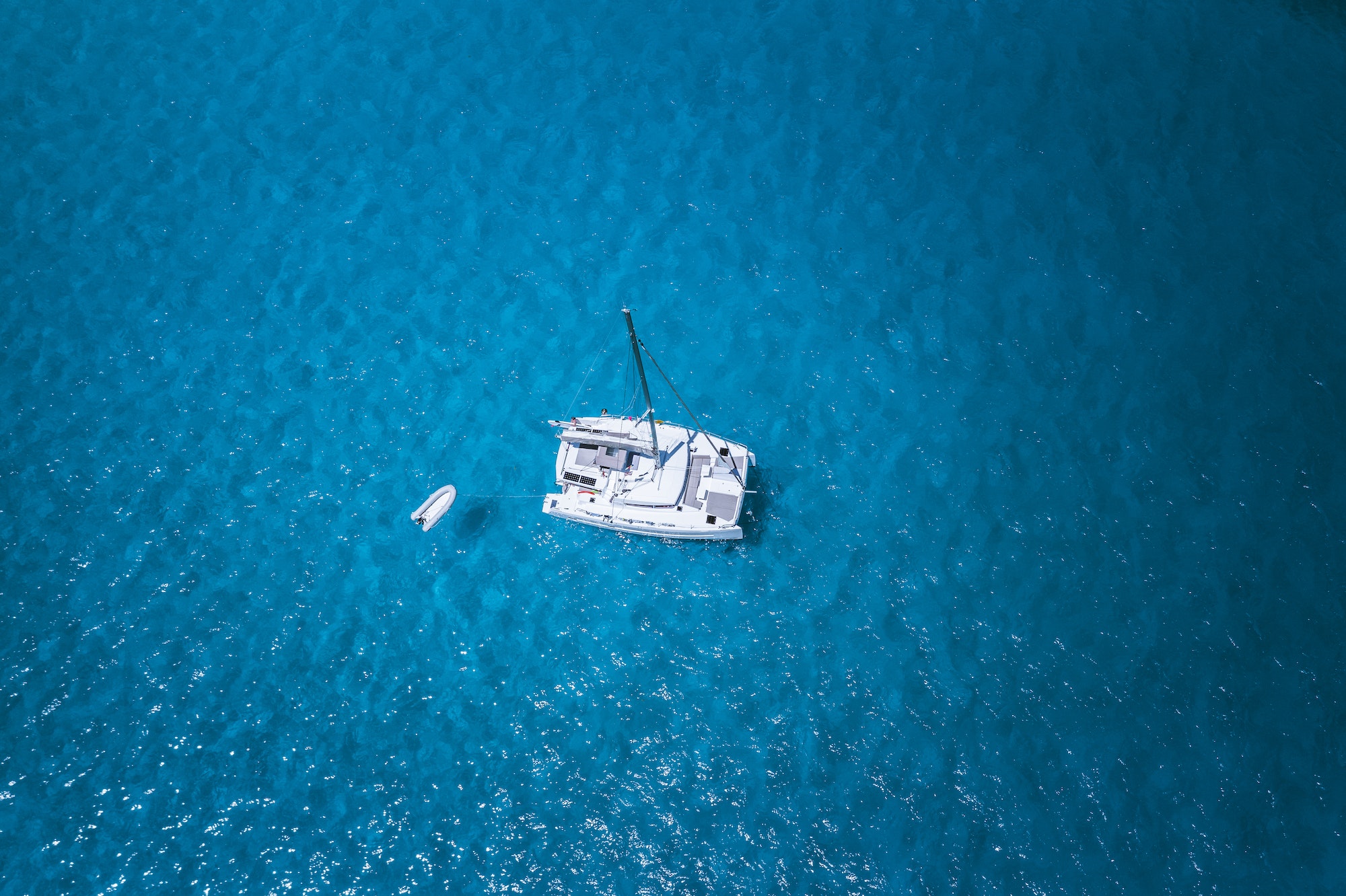 Aerial drone photo of catamaran boat at blue clear ocean water
