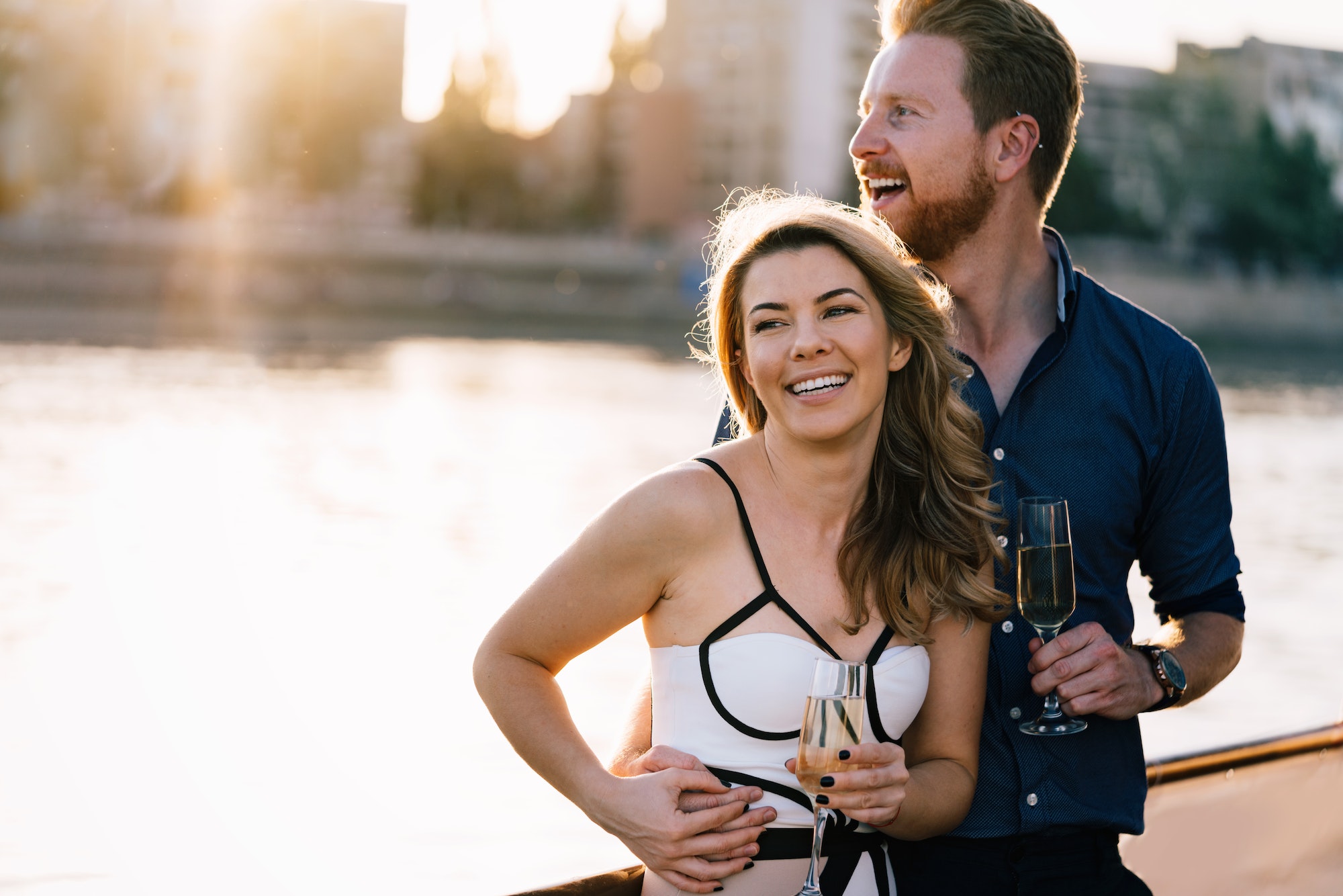 Happy young couple celebrating and drinking champagne a on a boat