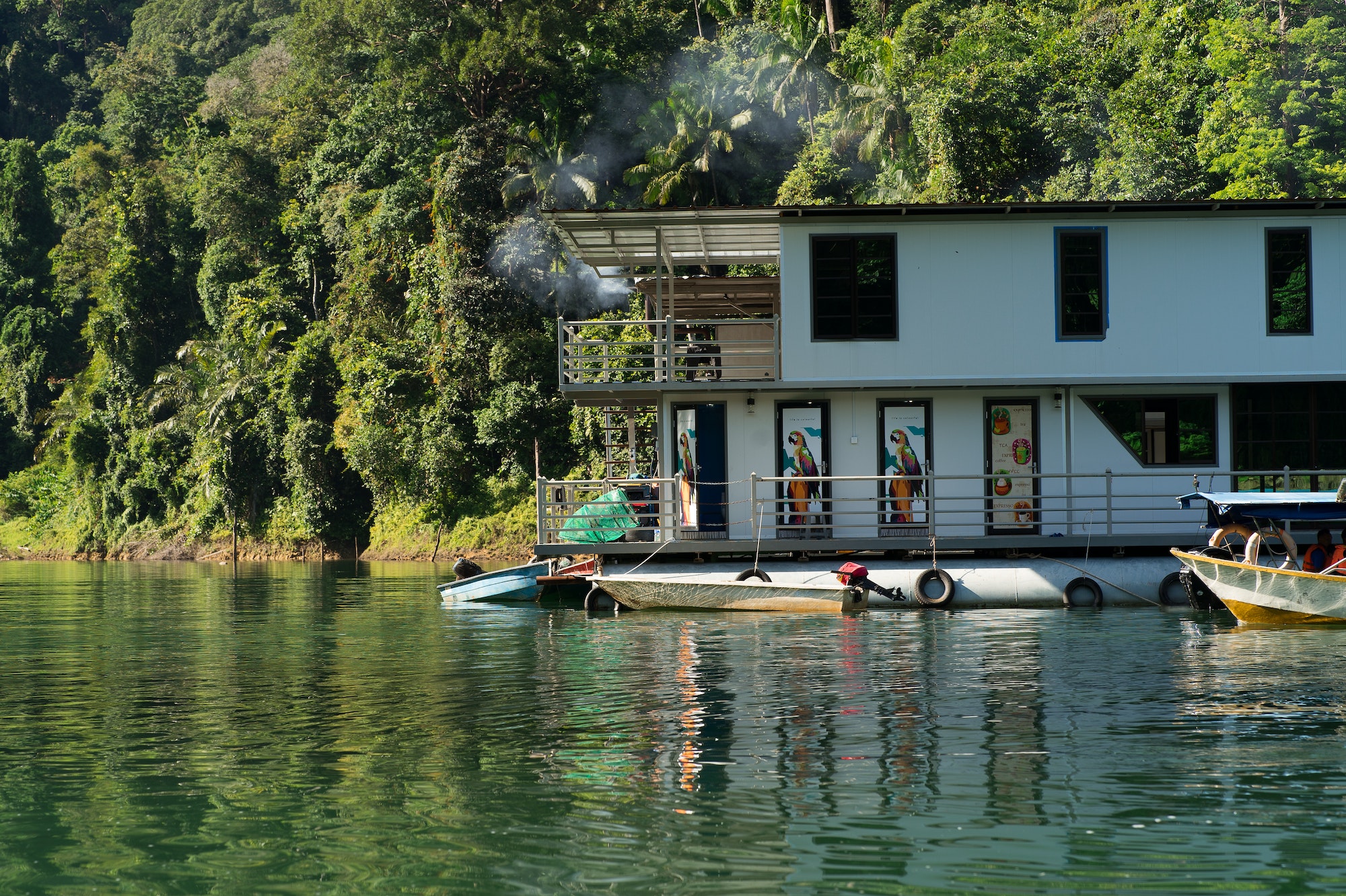 houseboat with smoke coming from the roof anchored on the serene idylic lake.