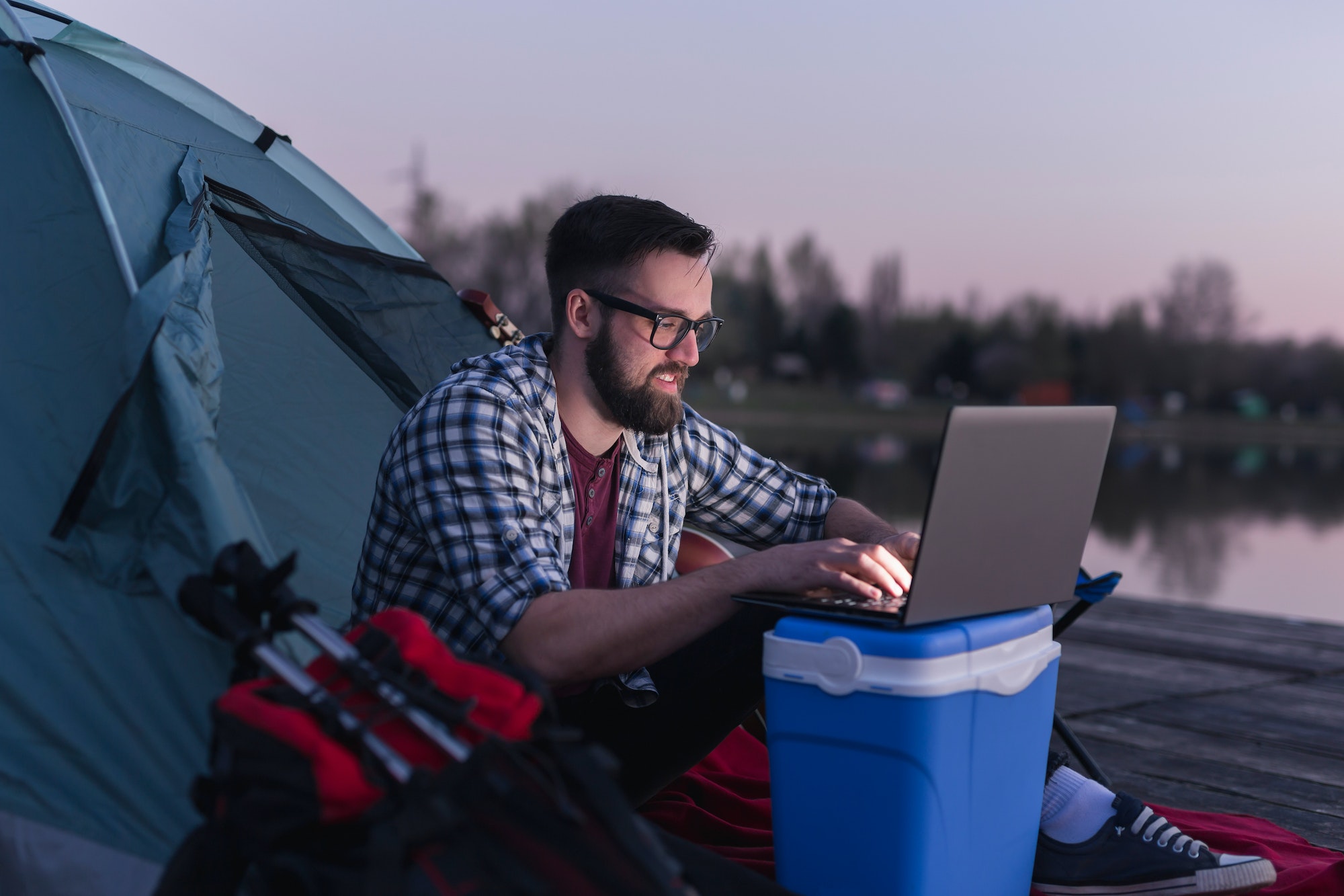Man using laptop while camping by the lake