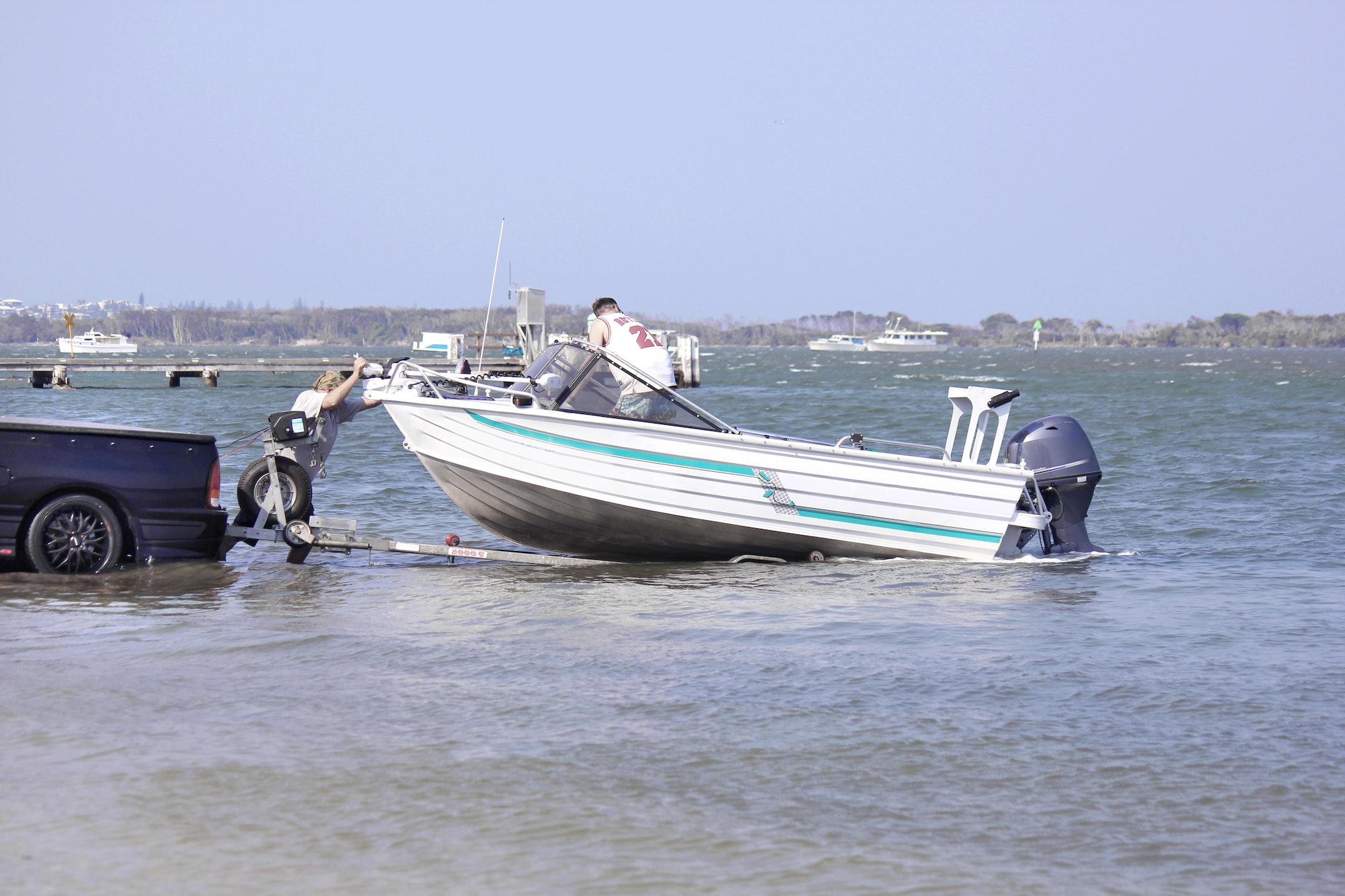 Fishermen launching a motor boat from the trailer into the water
